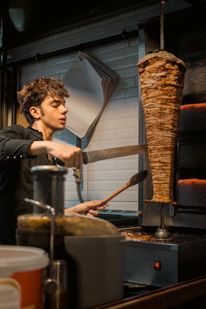 A chef skillfully slices a large doner kebab indoors in Istanbul, creating a delicious Turkish meal.